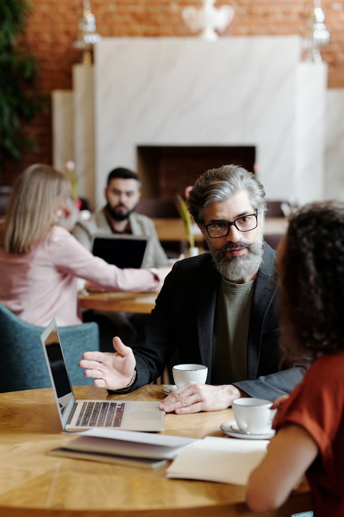 Colleagues having a discussion over coffee in a cozy cafe environment.